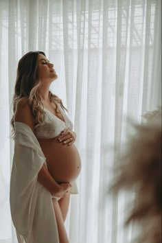 a pregnant woman standing in front of a window