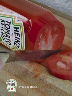 a tomato being sliced on top of a wooden cutting board