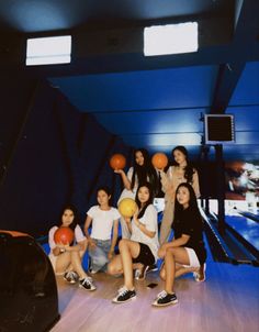 a group of young women sitting next to each other holding basketballs