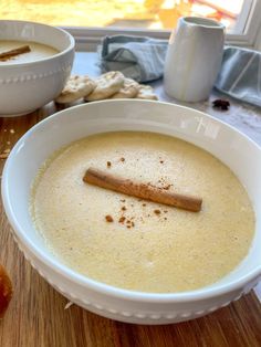 a white bowl filled with soup next to two bowls full of crackers and an apple