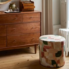 a bedroom with a dresser, mirror and chest of drawers in the corner next to a window