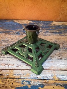 an old green metal object sitting on top of a wooden table