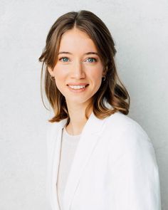 a woman in a white jacket smiling at the camera