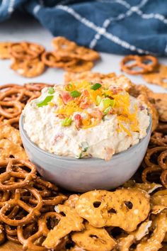 a bowl of dip surrounded by pretzels and crackers