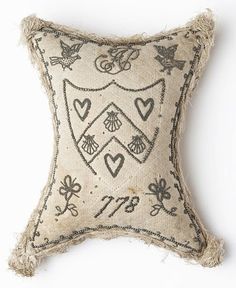 an embroidered pillow with hearts and flowers on the front is made out of jute