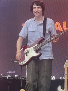 a young man holding a bass guitar on stage