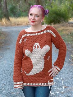 a woman standing in the middle of a road wearing an orange sweater with ghost on it