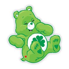 a green teddy bear sitting on its hind legs holding a four leaf clover sticker