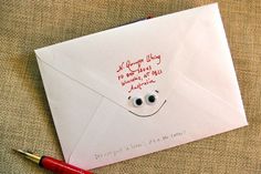 an envelope with a smiley face drawn on it and a red pen next to it