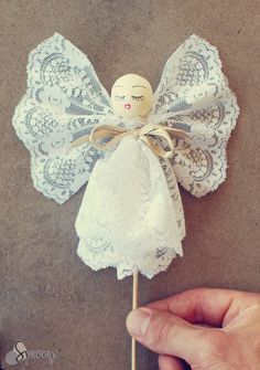 a hand holding a small white angel on a stick