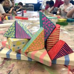 children are sitting at a table with brightly colored paper and crafting materials on it