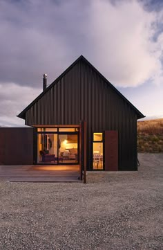 a black house is lit up by the light from the windows and door on the outside