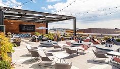 an outdoor seating area with tables, chairs and string lights strung across the roof top