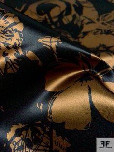 a close up view of a blue and gold flowered fabric with black, yellow, and white flowers on it