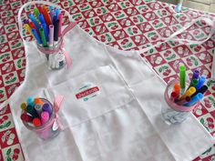 two aprons with markers on them are sitting on a red and white tablecloth