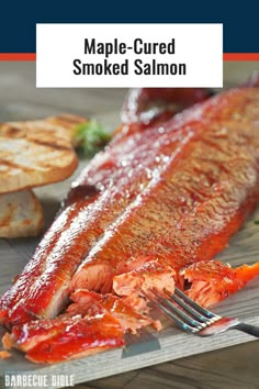 maple - glazed smoked salmon on a cutting board with a knife and fork next to it