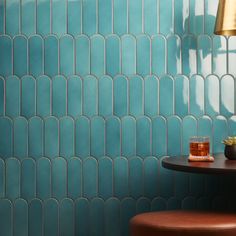 two stools in front of a blue tiled wall and table with drinks on it