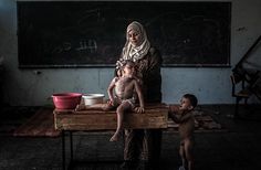 a woman and two children sitting at a table in front of a chalkboard with writing on it