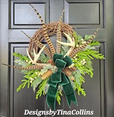 a wreath with deer antlers, pine cones and green velvet bow hanging on the front door