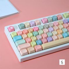 a computer keyboard with pastel colored keys on a pink surface