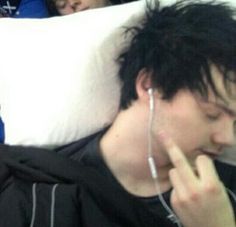 two people sleeping in the back of a car with headphones on and one person holding a cell phone to his ear