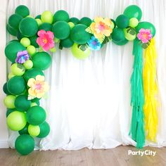 a green balloon arch with flowers and streamers