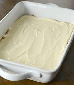 a white dish filled with frosting on top of a wooden table