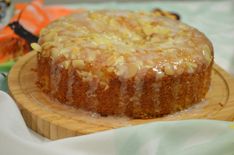 a cake sitting on top of a wooden plate covered in icing and nuts,