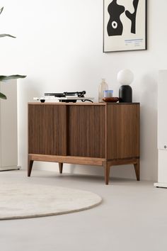 a wooden cabinet sitting in the middle of a living room next to a white rug