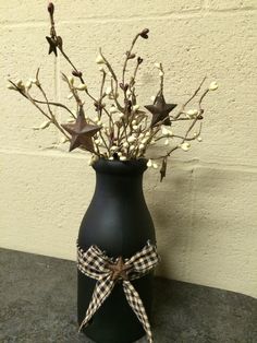 a black vase with white flowers in it and a ribbon tied around the top is sitting on a table