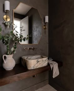 a bathroom sink sitting under a mirror next to a vase with a plant in it