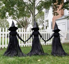 three black witches holding hands in front of a white picket fence