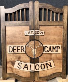 a wooden sign that says deer camp saloon on it's front and back doors