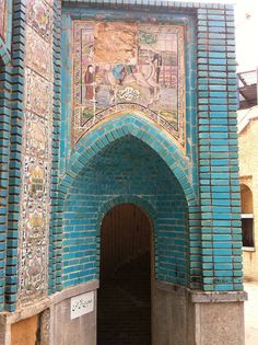 the entrance to an old building with blue bricks and carvings on it's sides