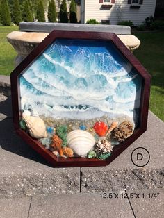 an ocean scene is displayed in a wooden frame on the sidewalk next to a house