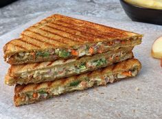 two grilled sandwiches sitting on top of a cutting board next to an apple slice