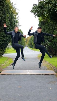 two men jumping in the air with their arms spread out and one man is wearing black