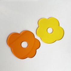 two yellow and orange flower shaped buttons on a white surface