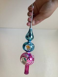 a person is holding some colorful glass items in their hand and they are hanging from a hook