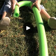 a man is using a green hose to clean the grass