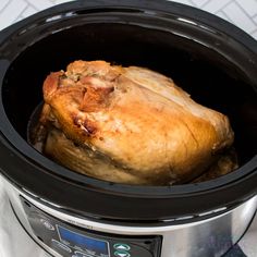 an uncooked chicken in the middle of a crock pot on top of a table