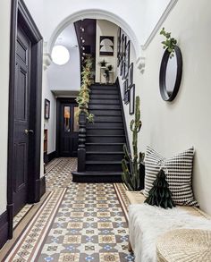 an entryway with stairs and potted plants on the floor, next to a bench