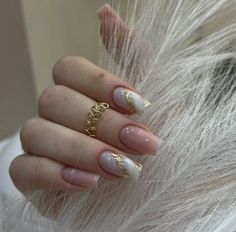 a woman's hand with white and gold manies on her nails, while she is