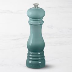 a green pepper mill sitting on top of a white counter