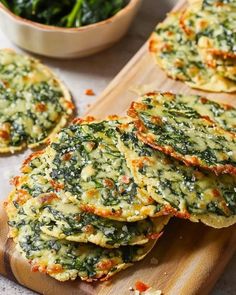 spinach fritters on a cutting board with a bowl of greens in the background