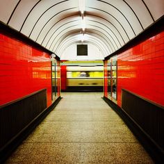 an empty subway station with red walls and doors