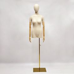 a mannequin is standing on top of a wooden stand with a metal base