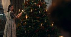 a woman standing in front of a christmas tree