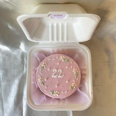 a pink cake in a plastic container with the number 22 on it's side