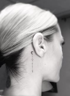 a woman's ear with a small tattoo on her left side behind the ear